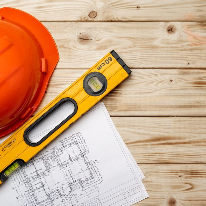Construction worker hardhat, blueprints and .construction level, top view Construction worker hardhat, blueprints and .construction level, top view